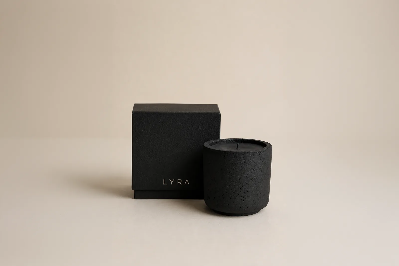 the andromeda candle beside its black gift box on a warm neutral ground