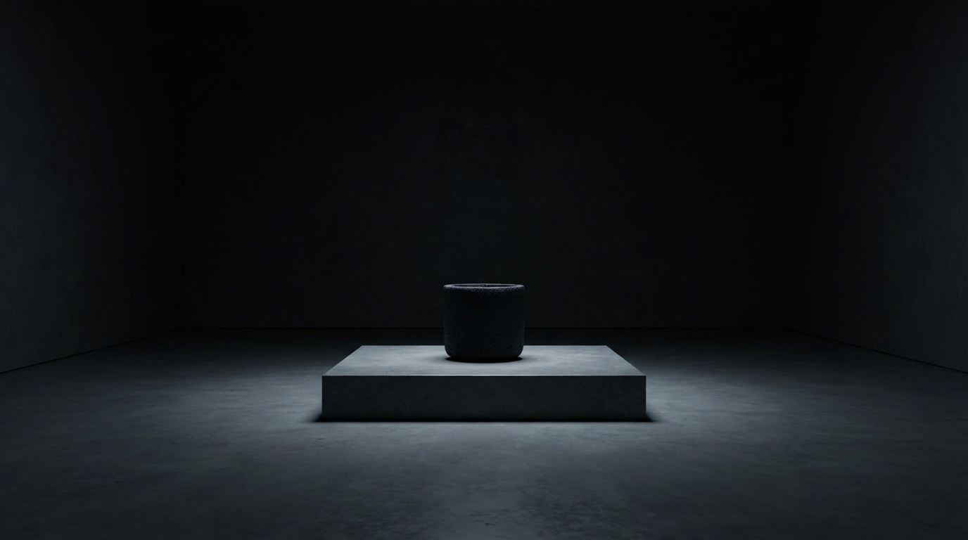 Black concrete candle isolated in a pool of cool light on a graphite plinth in a dark gallery space