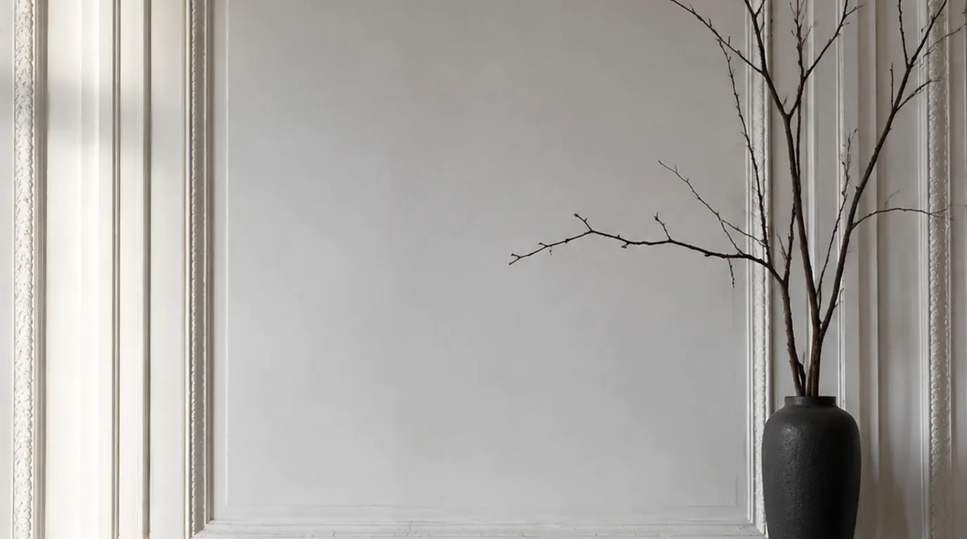 Black concrete candle next to an unlabeled stoneware vessel on a raw concrete shelf in a dim cool room